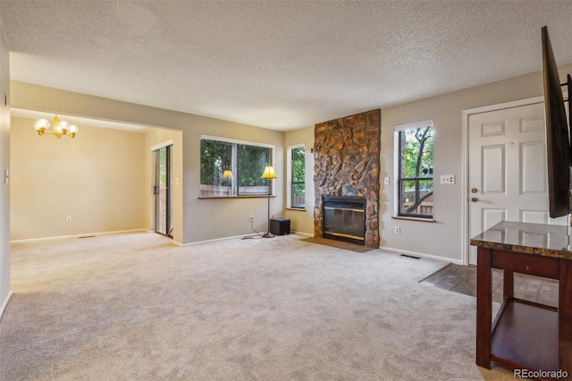 living area featuring a textured ceiling, a fireplace, visible vents, carpet, and an inviting chandelier