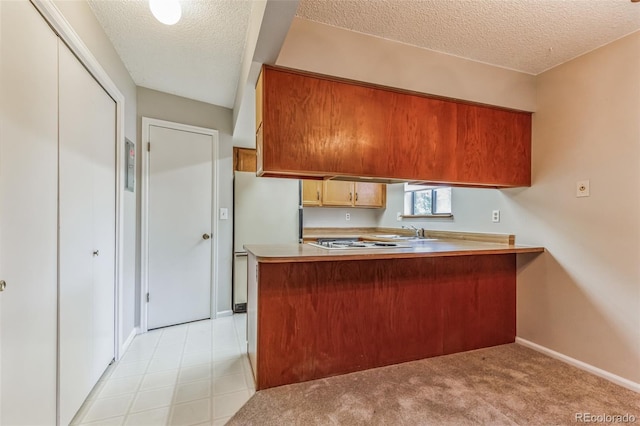 kitchen with light countertops, a sink, a textured ceiling, white appliances, and a peninsula