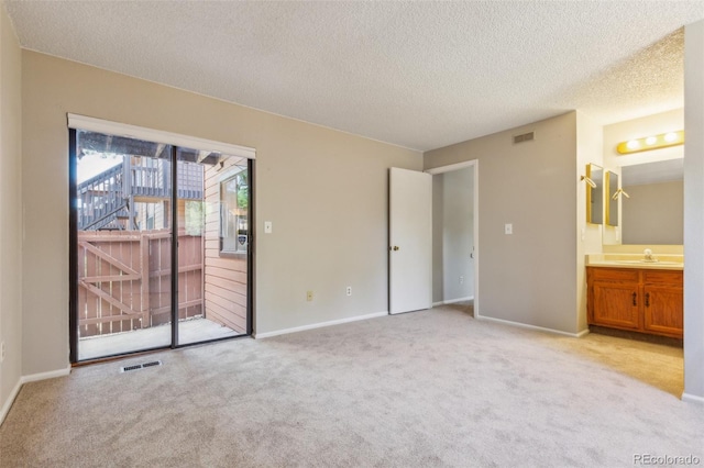 unfurnished bedroom featuring light carpet, a sink, visible vents, and access to exterior