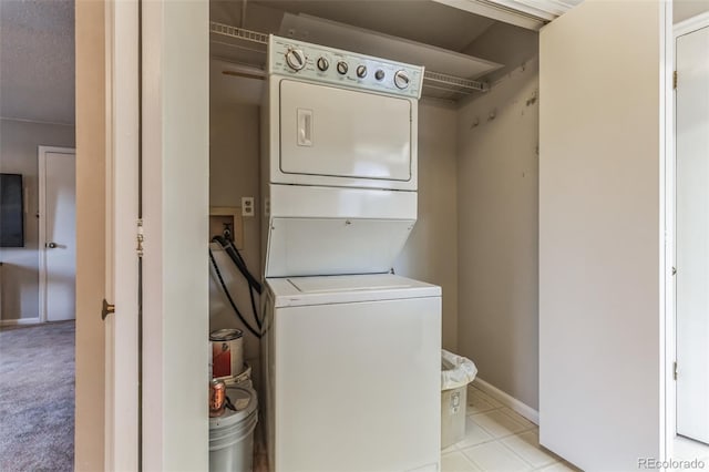 laundry area with laundry area, baseboards, and stacked washer / drying machine