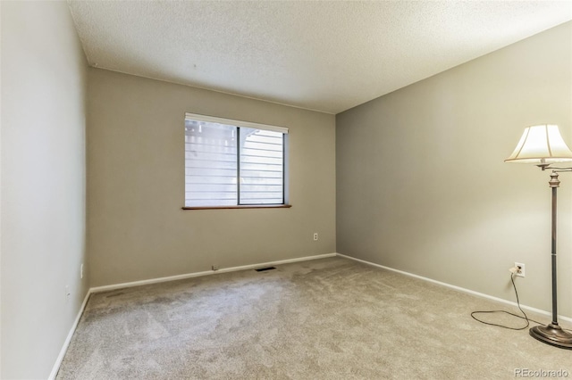 empty room featuring baseboards, a textured ceiling, visible vents, and carpet flooring