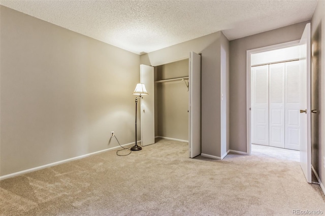 unfurnished bedroom with carpet flooring, a textured ceiling, and baseboards