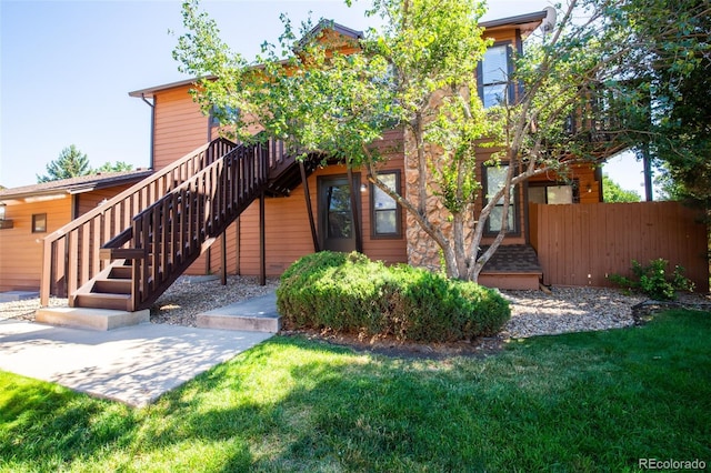 view of front of property featuring fence, a front lawn, and stairs