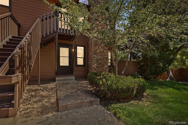 property entrance featuring fence and a lawn