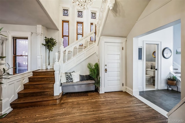 stairway with a chandelier, vaulted ceiling, and wood finished floors