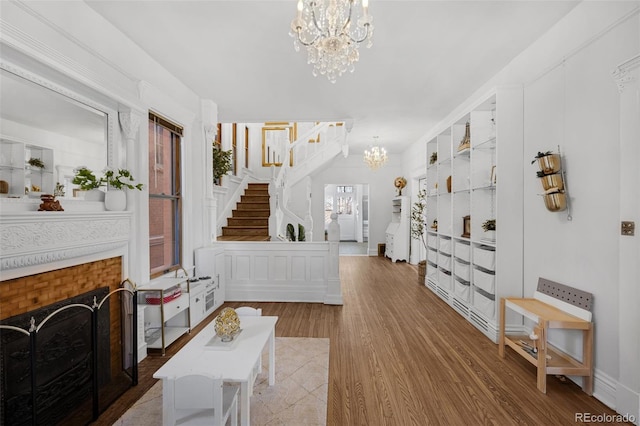 living room featuring a chandelier, stairs, a fireplace, and wood finished floors