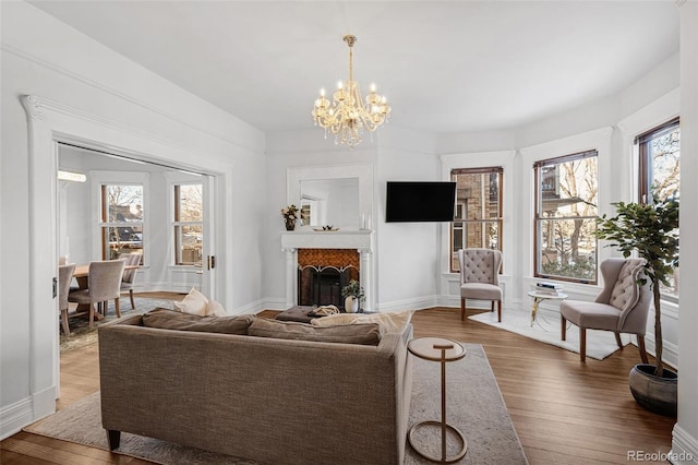 living area with a notable chandelier, a fireplace, baseboards, and hardwood / wood-style floors