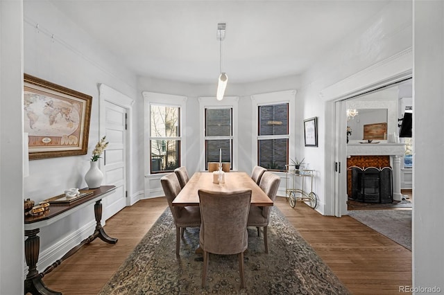 dining room featuring a fireplace, wood finished floors, and baseboards