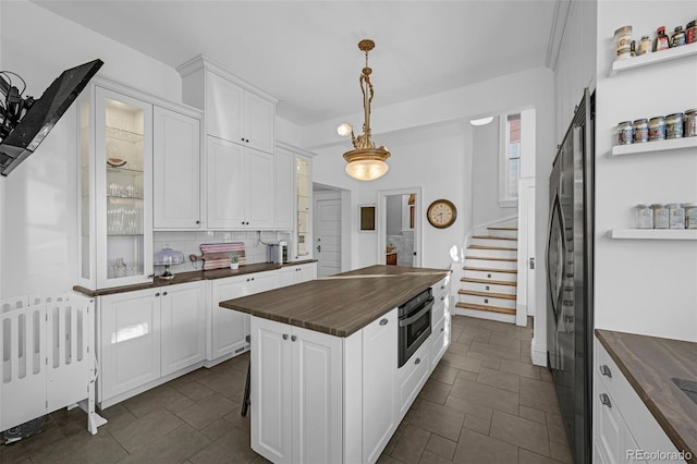 kitchen featuring stainless steel oven, white cabinetry, wooden counters, fridge, and glass insert cabinets