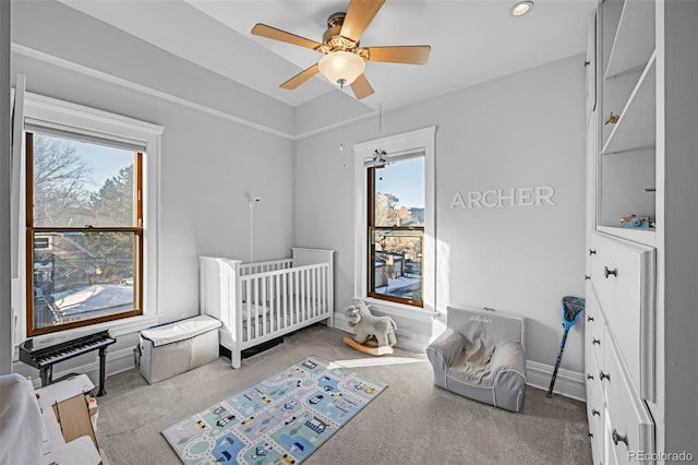 carpeted bedroom featuring a ceiling fan, multiple windows, and baseboards