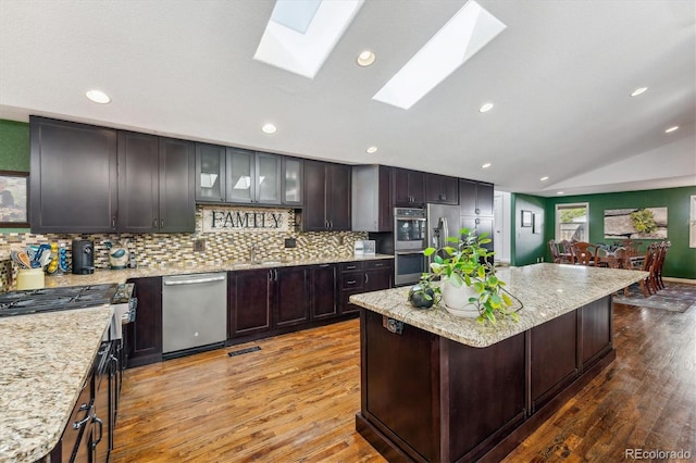 kitchen featuring dark brown cabinetry, a center island, a breakfast bar area, vaulted ceiling, and light hardwood / wood-style flooring