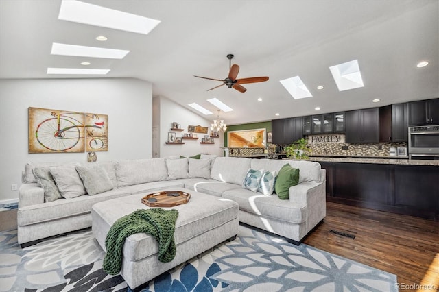 living room with hardwood / wood-style floors, vaulted ceiling, and ceiling fan with notable chandelier