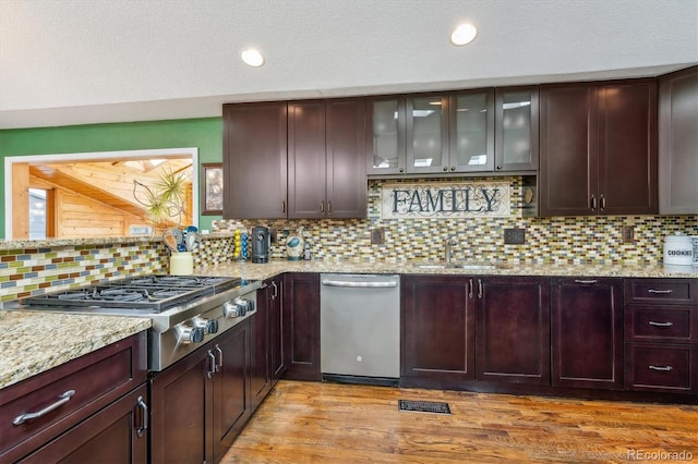 kitchen featuring light stone countertops, appliances with stainless steel finishes, sink, and light wood-type flooring