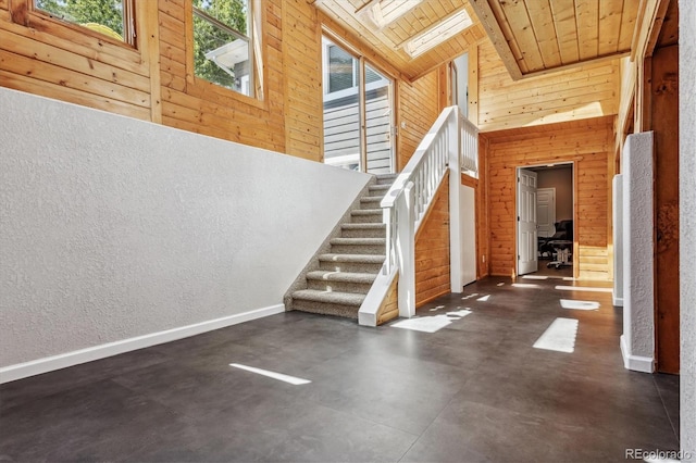 stairway featuring wood walls, wood ceiling, a skylight, and a towering ceiling