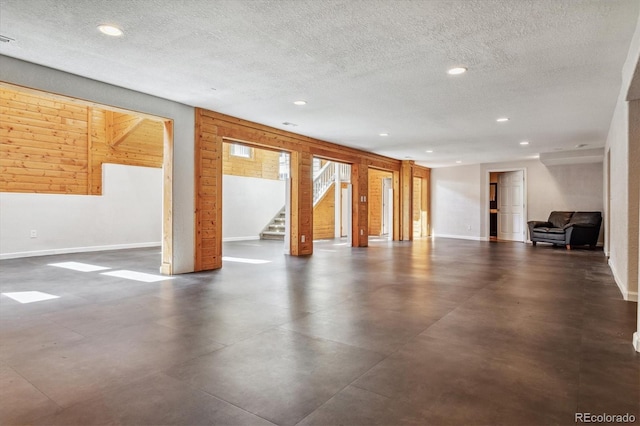 basement featuring a textured ceiling and wood walls