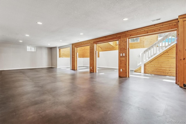 basement with wooden walls and a textured ceiling