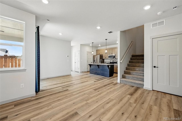 260 E 4th St, Berthoud, CO 80513 - unfurnished living room featuring recessed lighting, light wood finished floors, stairs, a sink, and baseboards