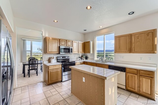 8915 S Field Ct, Littleton, CO 80128 - kitchen with stainless steel appliances, a center island, recessed lighting, a sink, and tile countertops