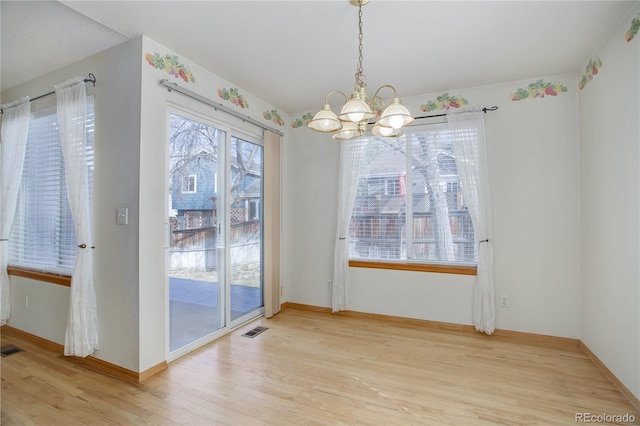 unfurnished dining area with a chandelier and light hardwood / wood-style flooring