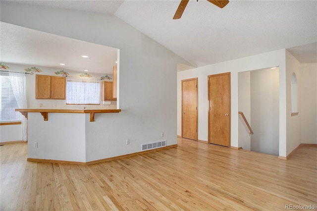 unfurnished living room featuring ceiling fan, light wood-type flooring, and lofted ceiling