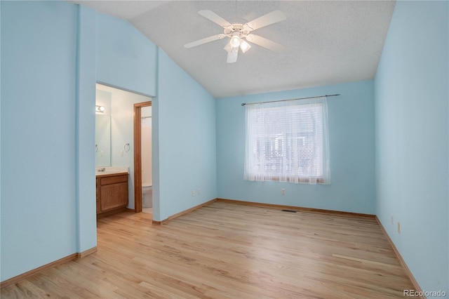 unfurnished bedroom with light hardwood / wood-style flooring, vaulted ceiling, ceiling fan, ensuite bathroom, and a textured ceiling