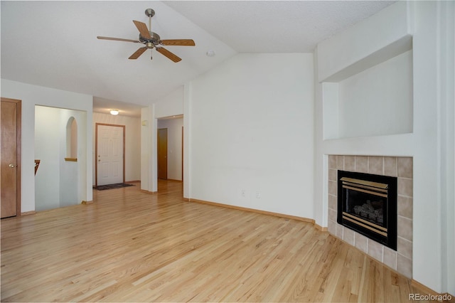 unfurnished living room featuring wood-type flooring, ceiling fan, a tile fireplace, and lofted ceiling