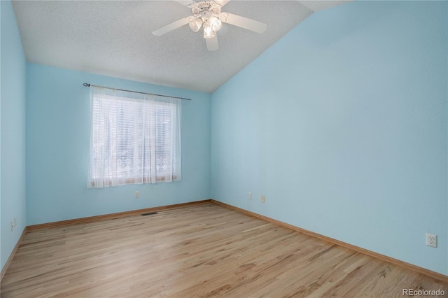 empty room with light wood-type flooring, ceiling fan, a textured ceiling, and lofted ceiling