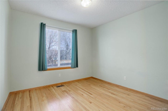 spare room featuring wood-type flooring and a textured ceiling