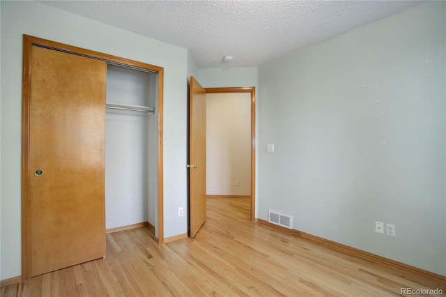 unfurnished bedroom featuring a closet, light hardwood / wood-style floors, and a textured ceiling