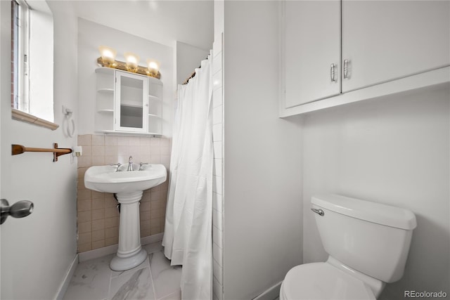 full bathroom with baseboards, marble finish floor, toilet, and tile walls
