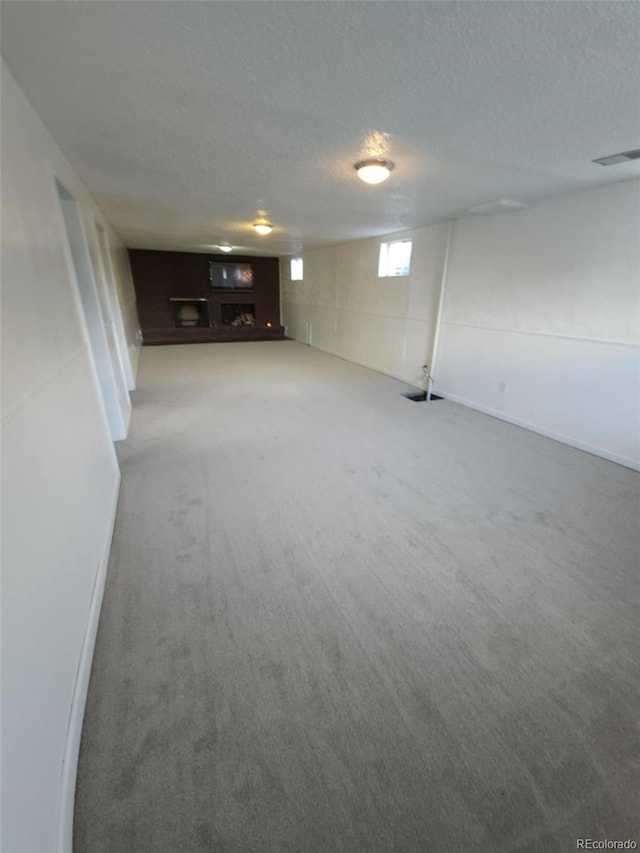 below grade area featuring carpet floors, a textured ceiling, and visible vents