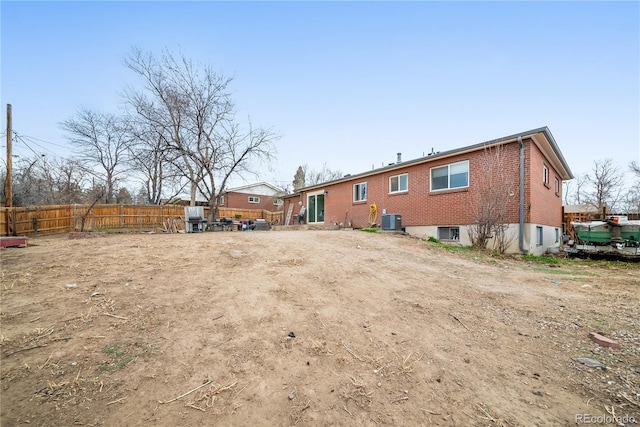 rear view of house featuring brick siding, fence, and cooling unit