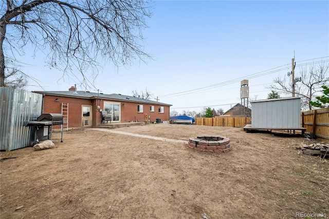 view of yard featuring a fenced backyard, an outbuilding, a fire pit, and a storage shed