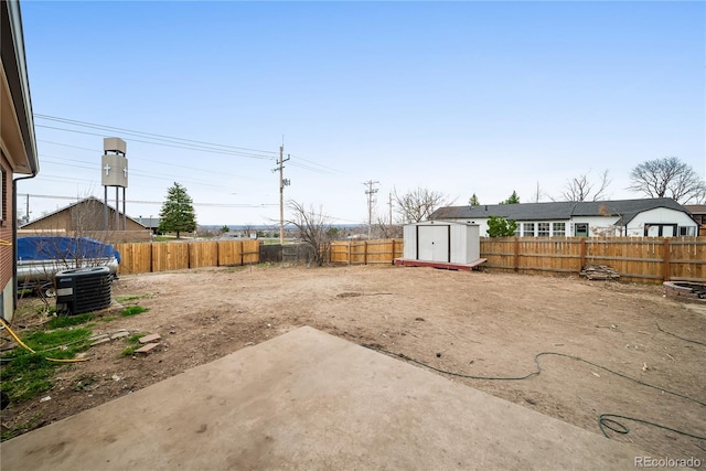 view of yard featuring central AC, a storage shed, a fenced backyard, an outbuilding, and a patio