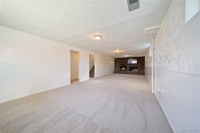 12024 W Maryland Dr, Lakewood, CO 80228 - unfurnished living room featuring a lit fireplace, a textured ceiling, stairs, carpet floors, and a wainscoted wall