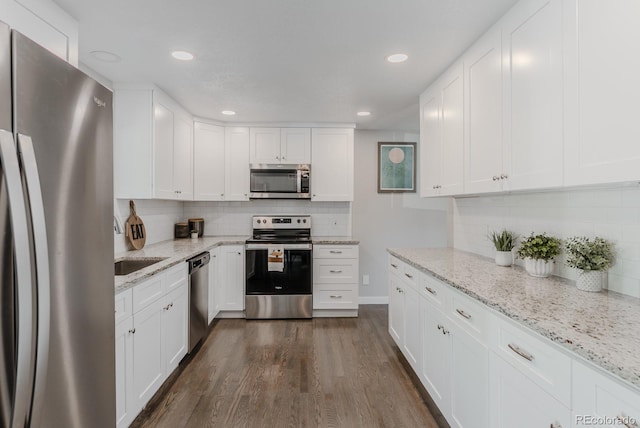 6059 Routt St, Arvada, CO 80004 - kitchen with appliances with stainless steel finishes, decorative backsplash, white cabinets, dark wood-style floors, and recessed lighting
