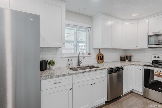 6059 Routt St, Arvada, CO 80004 - kitchen featuring appliances with stainless steel finishes, white cabinetry, decorative backsplash, wood finished floors, and recessed lighting