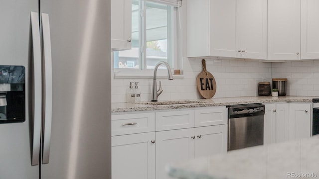 6059 Routt St, Arvada, CO 80004 - kitchen featuring appliances with stainless steel finishes, white cabinetry, tasteful backsplash, and light stone counters