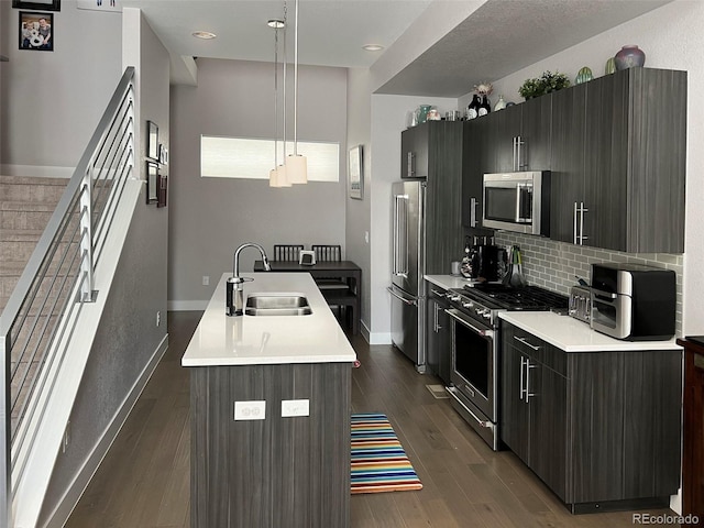 kitchen with sink, a kitchen island with sink, hanging light fixtures, dark hardwood / wood-style floors, and high end appliances