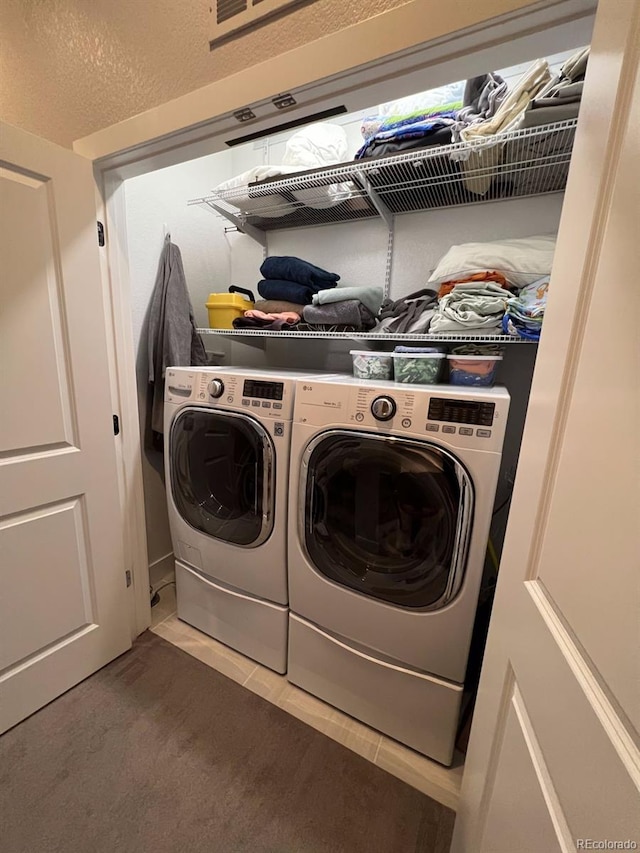 washroom with separate washer and dryer, tile patterned floors, and a textured ceiling