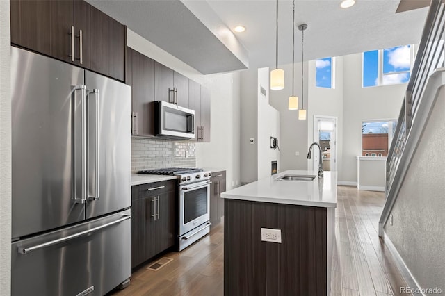 kitchen with wood finished floors, a sink, visible vents, appliances with stainless steel finishes, and tasteful backsplash