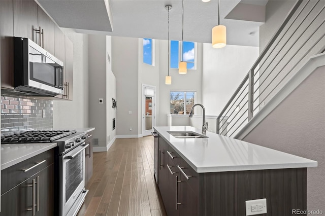 kitchen featuring light countertops, decorative backsplash, appliances with stainless steel finishes, a sink, and wood finished floors