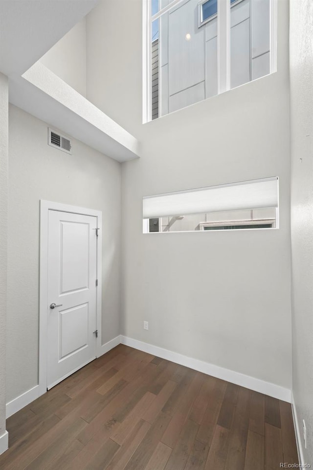 empty room featuring wood finished floors, visible vents, and baseboards