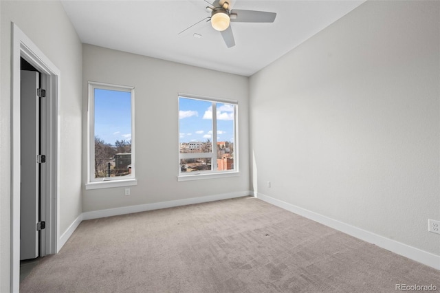 carpeted empty room with ceiling fan and baseboards