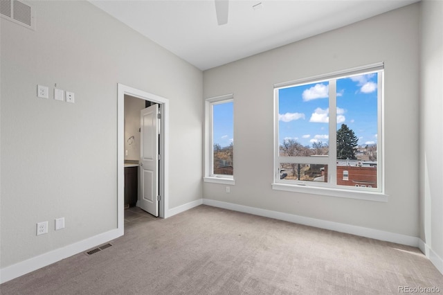 unfurnished bedroom with multiple windows, visible vents, and light colored carpet