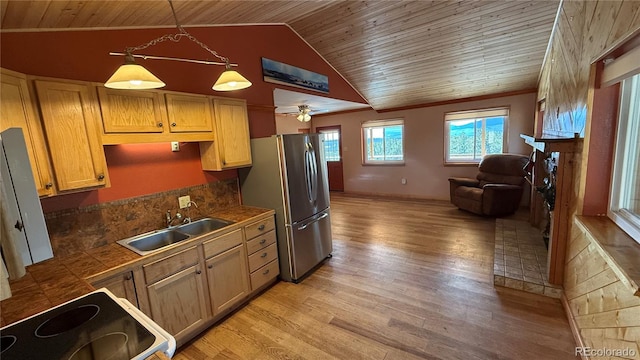 kitchen with stainless steel refrigerator, sink, light hardwood / wood-style flooring, pendant lighting, and vaulted ceiling