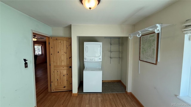 laundry room with ceiling fan, wood-type flooring, and stacked washer and dryer