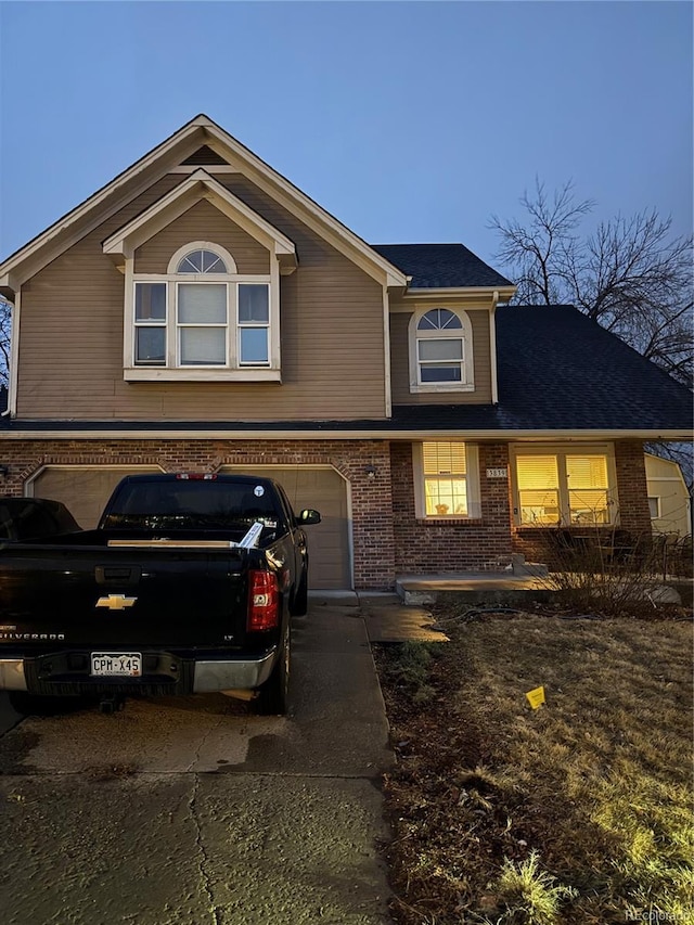 view of front facade with an attached garage, driveway, and brick siding