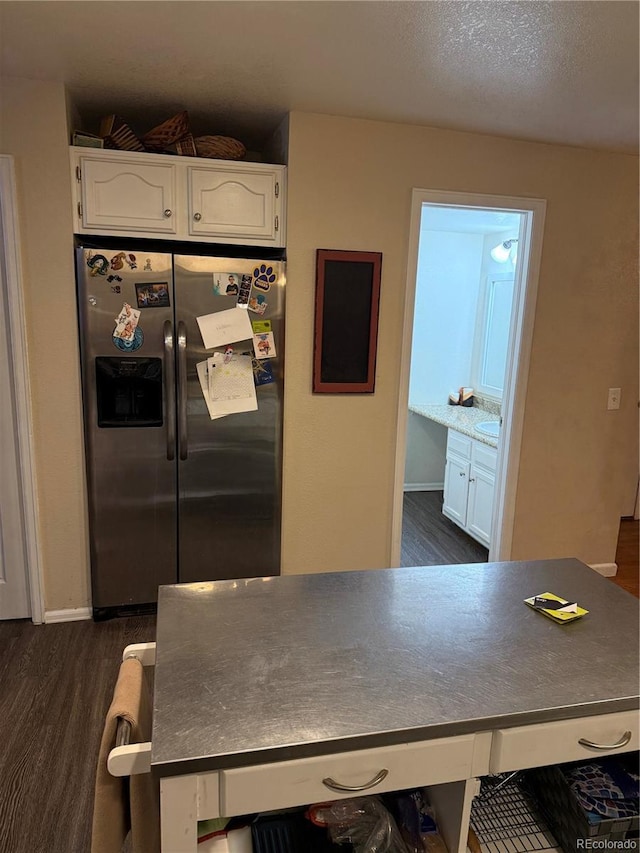 kitchen with stainless steel refrigerator with ice dispenser, dark wood-type flooring, white cabinets, a textured ceiling, and baseboards