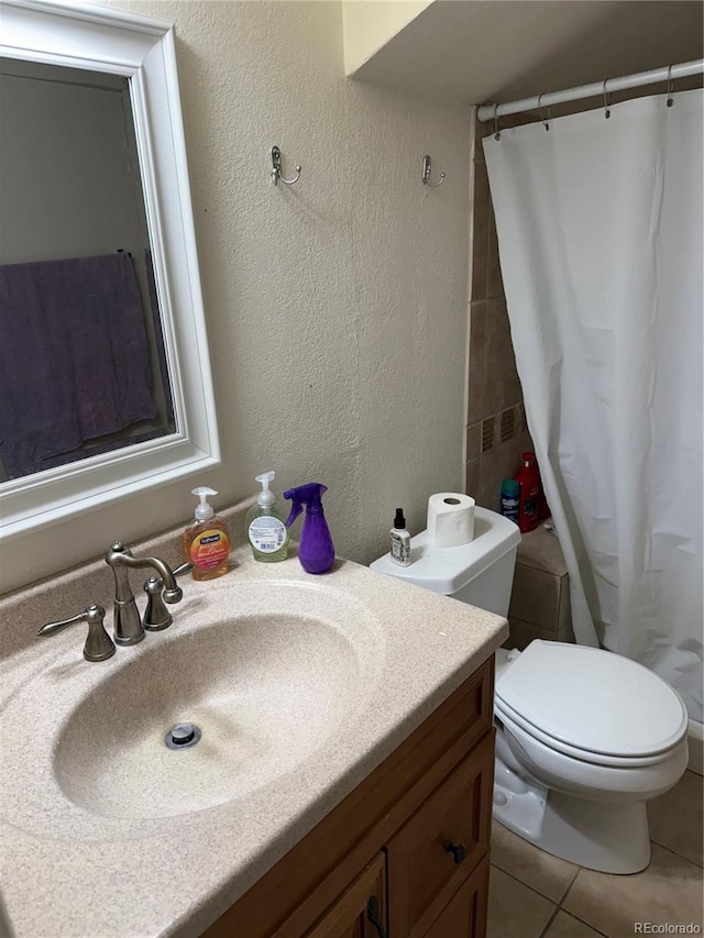 bathroom featuring a textured wall, toilet, a shower with shower curtain, vanity, and tile patterned floors